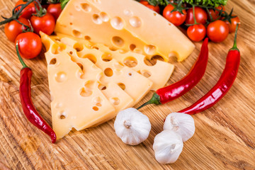 Cheese with fresh vegetables on a wooden background