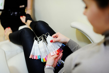 The girl in the beauty salon chooses the color of the nail polish. pedicure