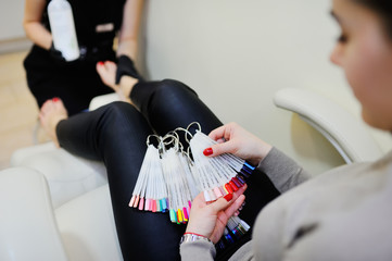 The girl in the beauty salon chooses the color of the nail polish. pedicure