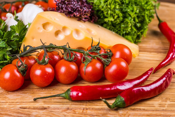 Cheese with fresh vegetables on a wooden background