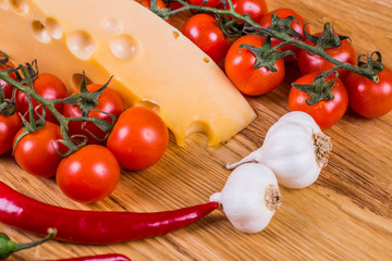 Cheese with fresh vegetables on a wooden background