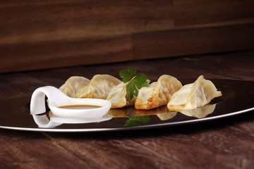 A plate of Japanese gyoza dumplings sitting on a rustic wooden table.