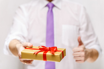 Male hands holding a gift box. Present wrapped with ribbon and bow. Christmas or birthday package. Man in white shirt and necktie.