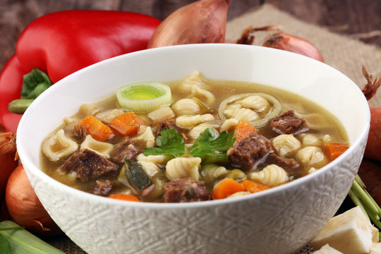 Clear soup with beef and noodles. Broth with carrots, onions various fresh vegetables in a pot