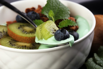 Smoothies bowl - matcha green tea breakfast superfoods topped with chia, pumpkin seeds, bee pollen, granola, kiwi and blueberries.