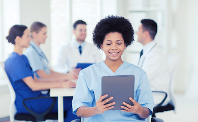Fototapeta premium happy doctor with tablet pc over team at clinic