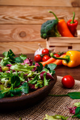 Provence salad. Leaves of endive or chicory, lamb and rose salad. Cherry tomato, pepper and brocoli. Raw vegetables. On wooden table.