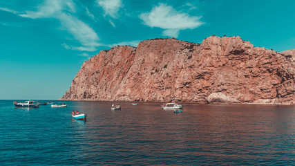 Fototapeta na wymiar Boats with the fishermen in the sea near rocky coast