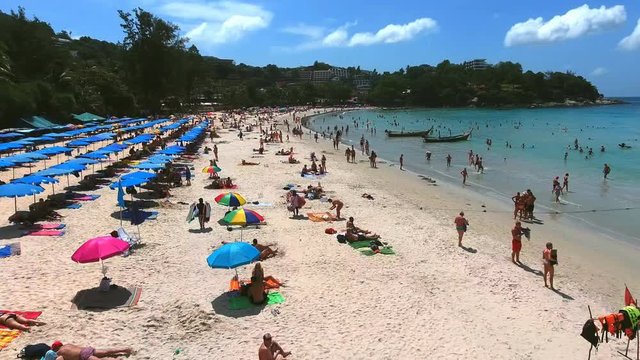 PHUKET, THAILAND - 20 JAN 2017: Aerial view of people swim in sea near beach with sunbeds and parasols at summer sunny day