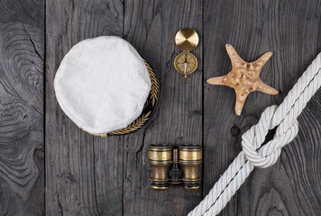 Captain's cap, vintage binoculars, a compass on an old wooden table,Marine concept