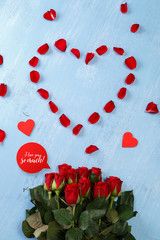 Heart of red rose petals on blue painted rustic background. I love you so much. Fresh natural bouquet of flowers.