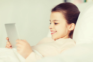 happy girl lying in bed with tablet pc at home