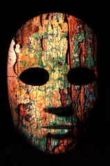 Textured mask with cracked rough wood  painted surface, neutral expression on dark background.
