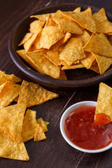 Nachos chips. Delicious salty tortilla with sweet salsa or chilli sauce on wooden background. Snack on rustic plate.