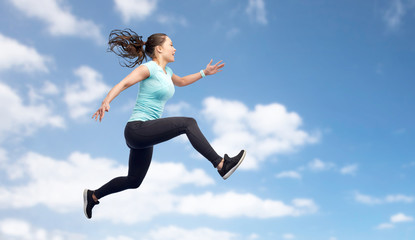 happy sporty young woman jumping in blue sky