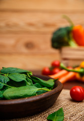 Spinach leaves in bowl. Raw fresh vegetable. Fresh natural plant leaf. Organic bio food on rustic wooden table.