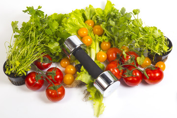 Concept of healthy active lifestyle and diet control. Red  tomatoes, parsley, cilantro, dill,, lettuce. Fitness dumbbell . 