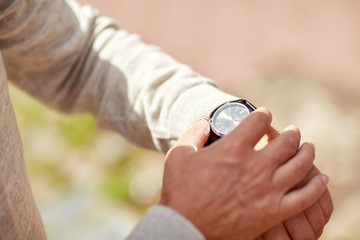 senior man checking time on wristwatch outdoors