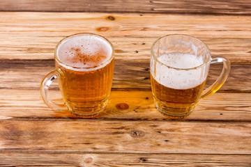 Mugs of cold beer on wooden table