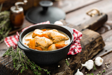 Meat stewed with carrots in sauce and spices in cast iron pan on dark wooden rustic background