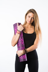 Studio shot of young beautiful teenage girl holding yoga mat and posing ready for gym