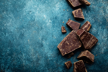 Dark chocolate pieces crushed on a dark background, view from above