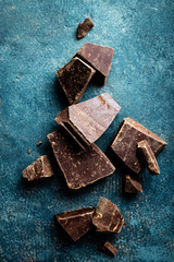 Dark chocolate pieces crushed on a dark background, view from above