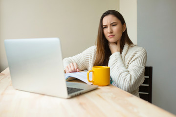 Fototapeta premium Sick girl at the laptop computer feeling hard pain in her throat working from home in cozy clothes. Ill woman studing