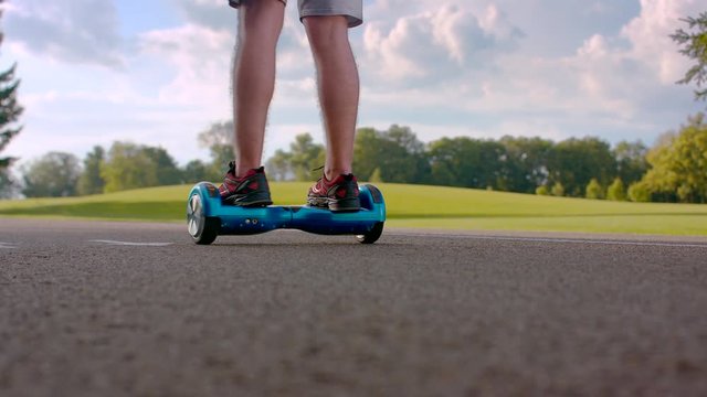 Man turn around on electric self balance board outdoors. Closeup of man legs on gyro board. Man having fun on gyroscooter at asphalt road. Modern eco transport. Driving gyro board