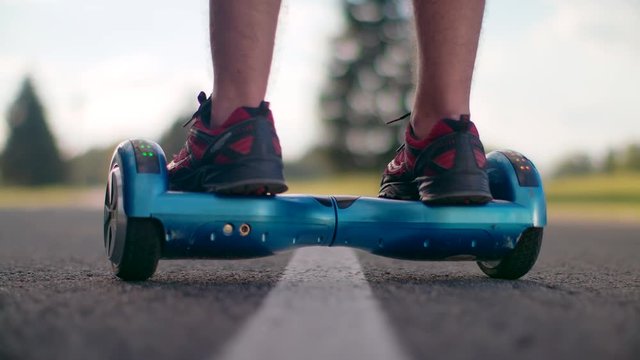 Man using self balance scooter at park road. Closeup of man legs on two wheels electric gyro scooter at asphalt road. Close up of man legs on gyroscooter. Personal eco transport