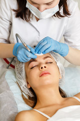Obraz na płótnie Canvas Dermabrasion girl's forehead. Machine cosmetology. Spa. Facial Rejuvenation. Mechanical peeling skin.