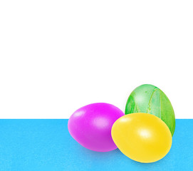 Obraz na płótnie Canvas Three bright colorful easter eggs. Pink, yellow, green easter eggs on blue uneven background on white background