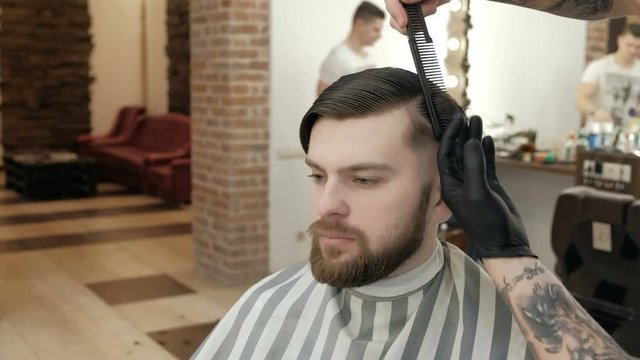 Master makes beards correction in background salon barbershop