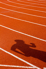 Shadow of man on red running track. Sport concept