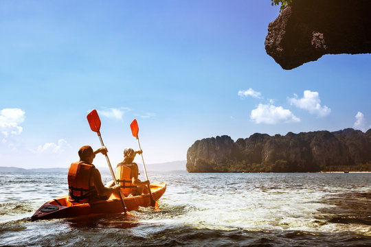 Couple canoeing at sea island backdrop