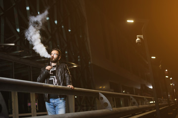 Vaping man holding a mod. A cloud of vapor. Stylish hipster with vape.