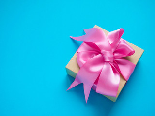 one gift box with pink satin ribbon on a blue background, copy space for text