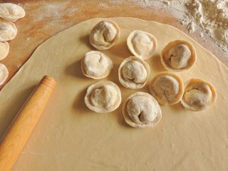 Raw dumplings and rolling pin on rolled dough, preparation of dumplings