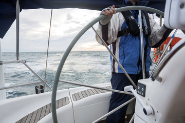 Midsection Of Man Steering Wheel Of Yacht In Sea