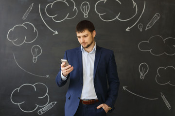 Young man writing sms standing by concrete wall