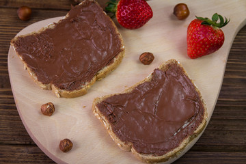 Bread with chocolate cream and strawberry on a wooden board