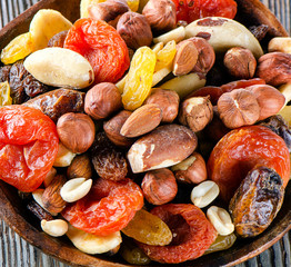 Mix nuts and dried fruits on a rustic wooden background.