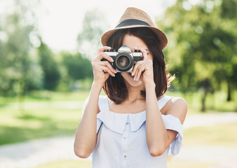Young beautiful tourist woman taking photographs with retro styled digital photo camera