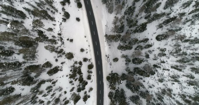 Aerial view of winter forest and asphalt road in high mountains