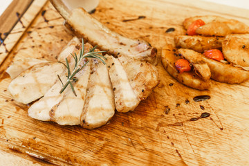 Grilled pork chops , sliced potatoes and carrots on wooden board