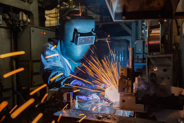 Worker is welding  in car factory
