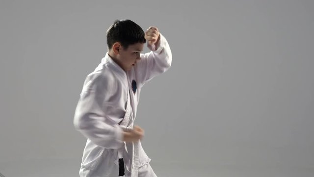 A young karateka stands in profile and trains two  self defence blocks in studio