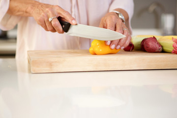 Obraz na płótnie Canvas older woman cutting fresh vegetables in kitchen