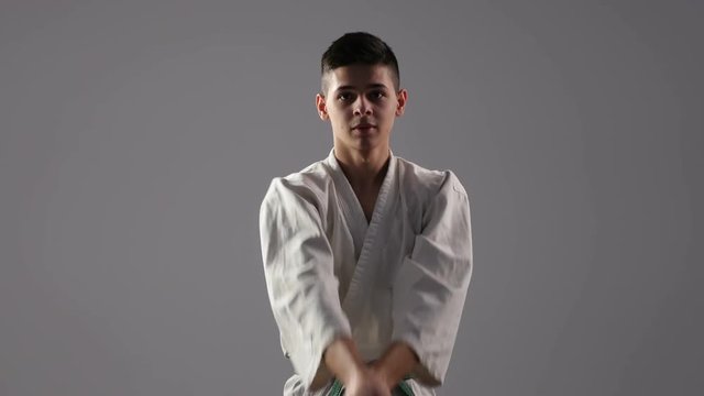 Ancient katana usage at a workout of a young sportsman in white kimono in studio