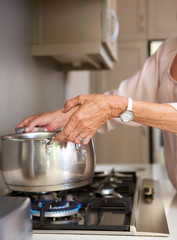 older woman boiling water in pot on stove top